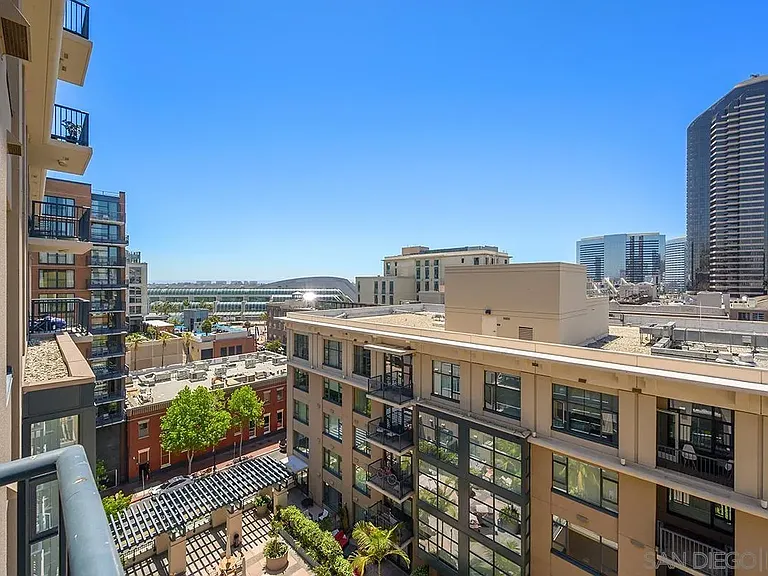 Balcony view from a California house of a modern city with a green courtyard and trees below.