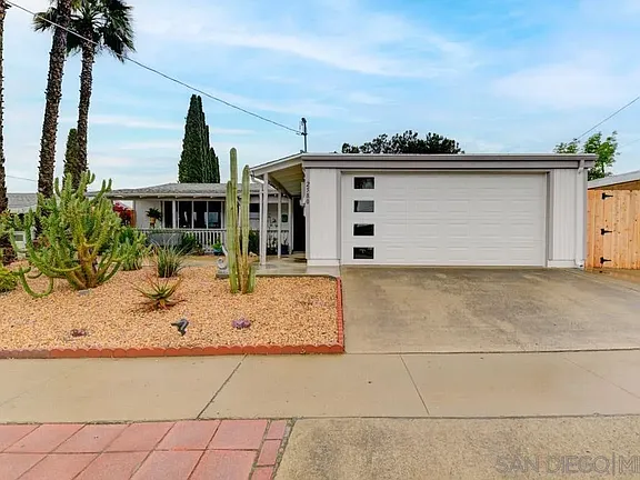 California house with white facade, garage door with many windows, front yard.